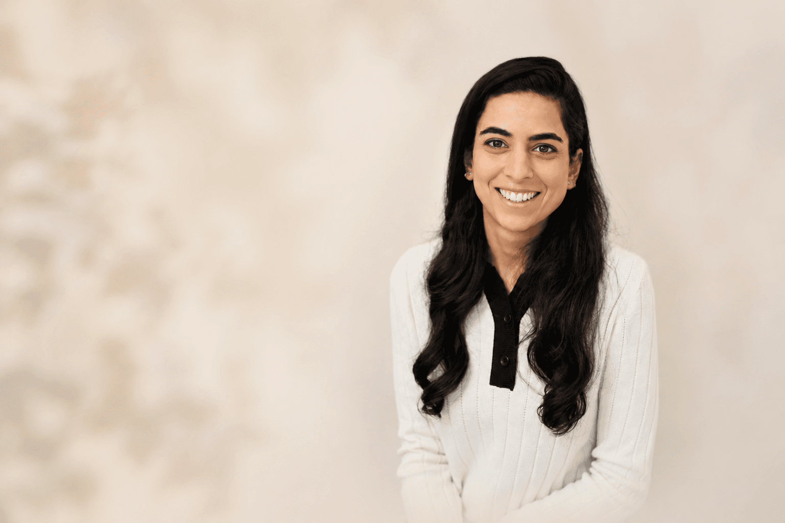 Anjali Singh-Mitter, psychotherapist and neurofeedback practitioner, in a softly lit portrait with warm, out-of-focus negative space to her left.